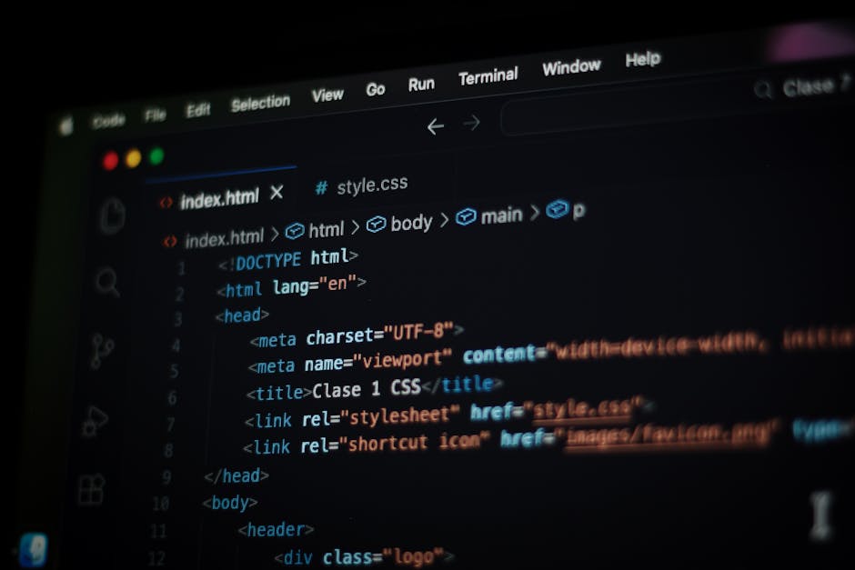 A close-up view of a laptop computer displaying a coding interface with multicolored lines of code on the screen, placed on a wooden desk. To the right of the laptop, there is a ceramic coffee mug wit